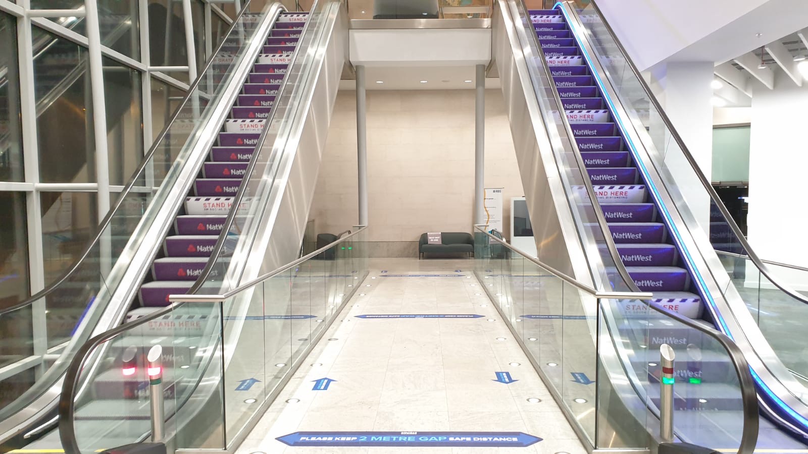 Social distance signs on two escalators